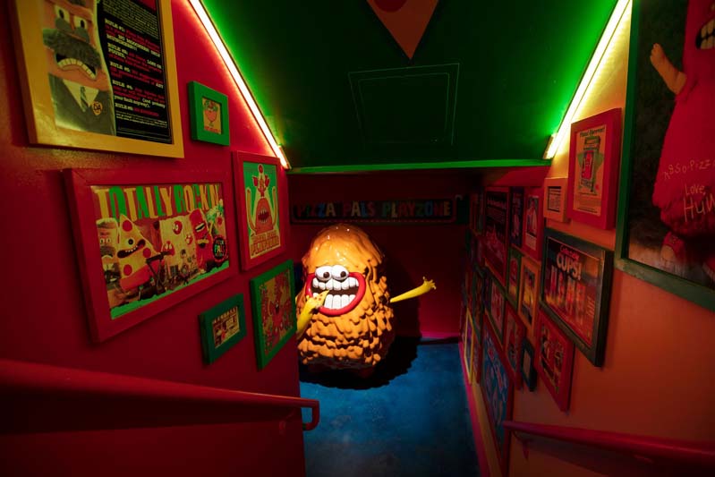 Looking down a stairwell at a melty hamburger character on the left at Meow Wolf Denver