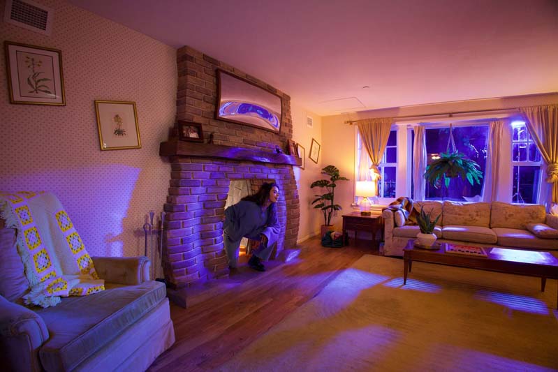 person coming out of a fireplace in a seemingly normal home at Meow Wolf