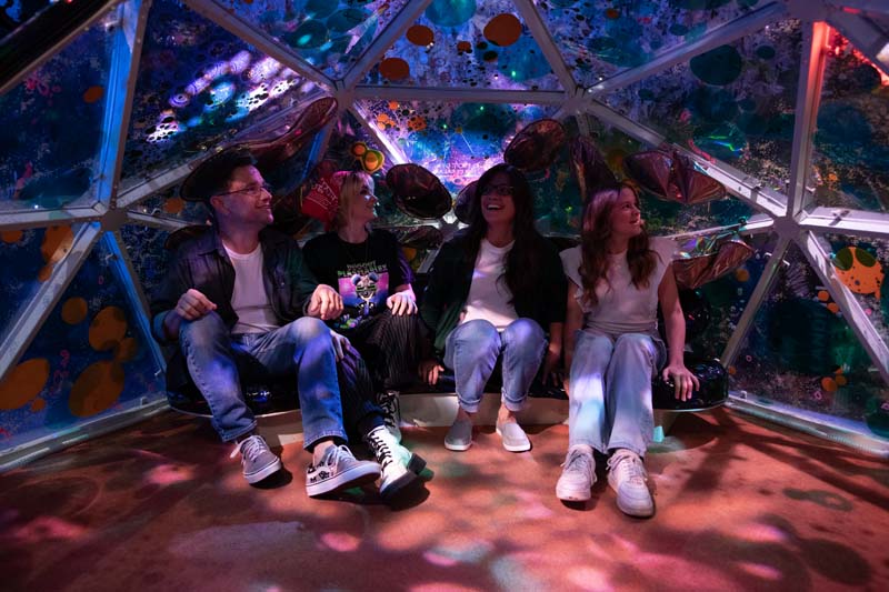 group of young people sitting inside a giant globe at Meow Wolf