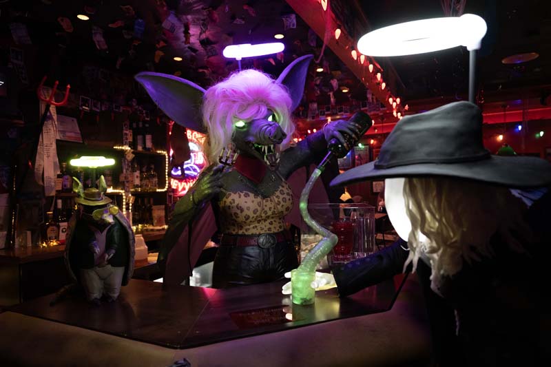 an angel bat bartender pouring a drink for an angel human with a cowboy hat and leather jacket inside Cowboix Hevvven