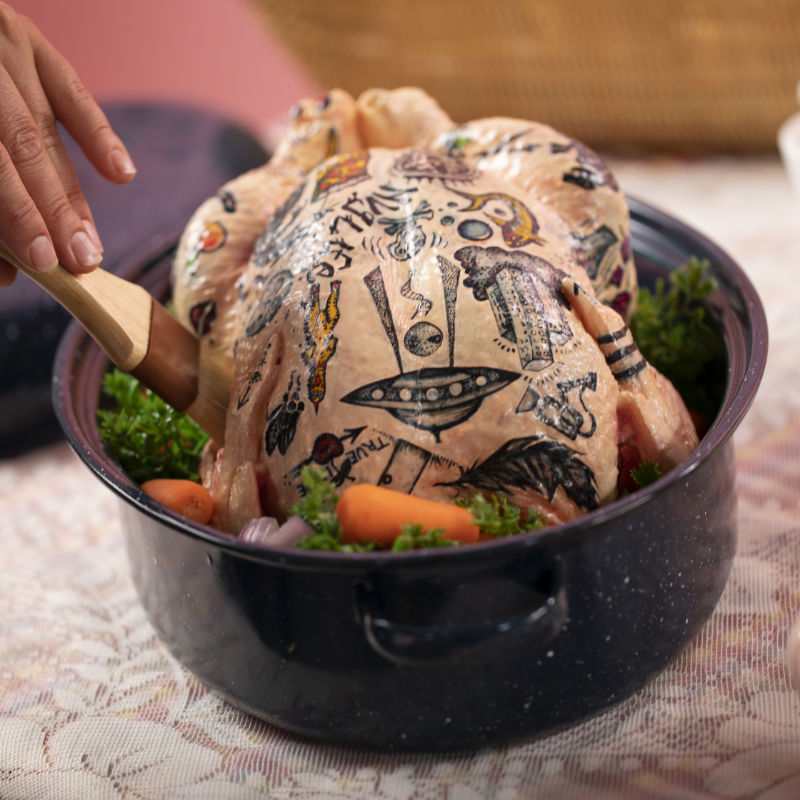 Chicken with tattoos all over it in a pot