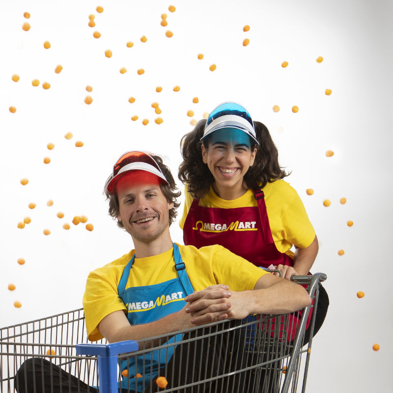 Omega Mart employees, one standing in behind a shopping cart and one in the cart