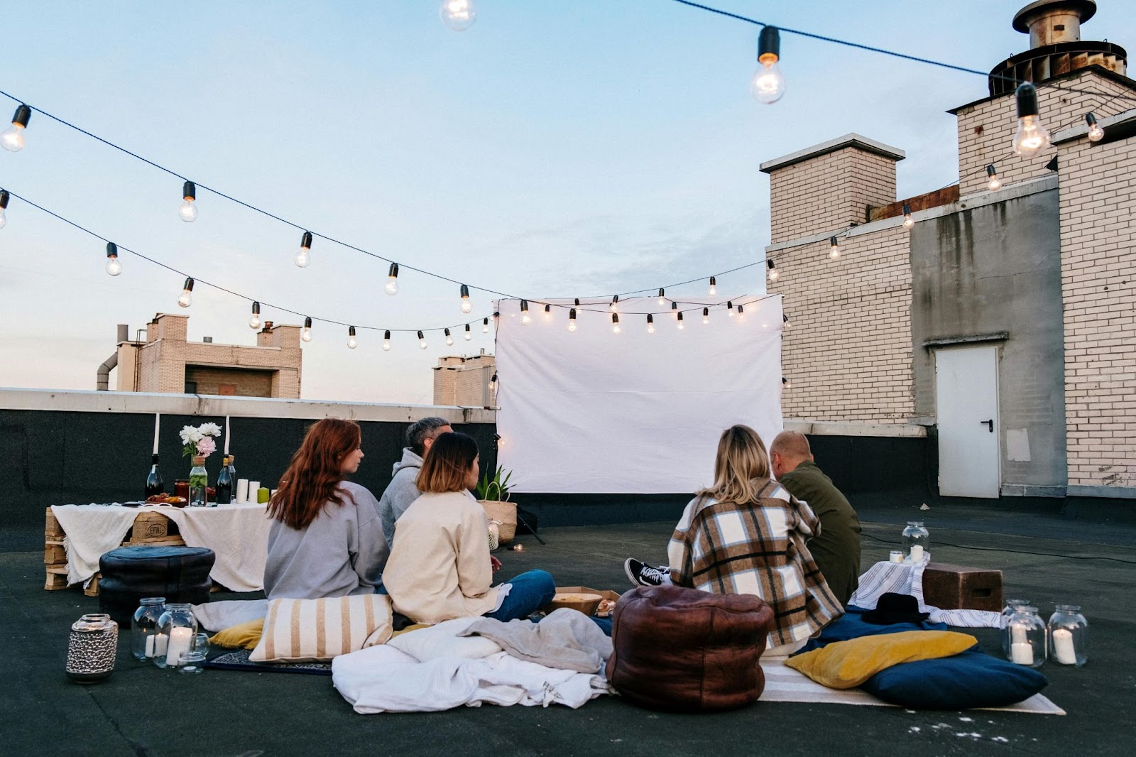 Rooftop movie with people enjoying a picnic on a unique date night.