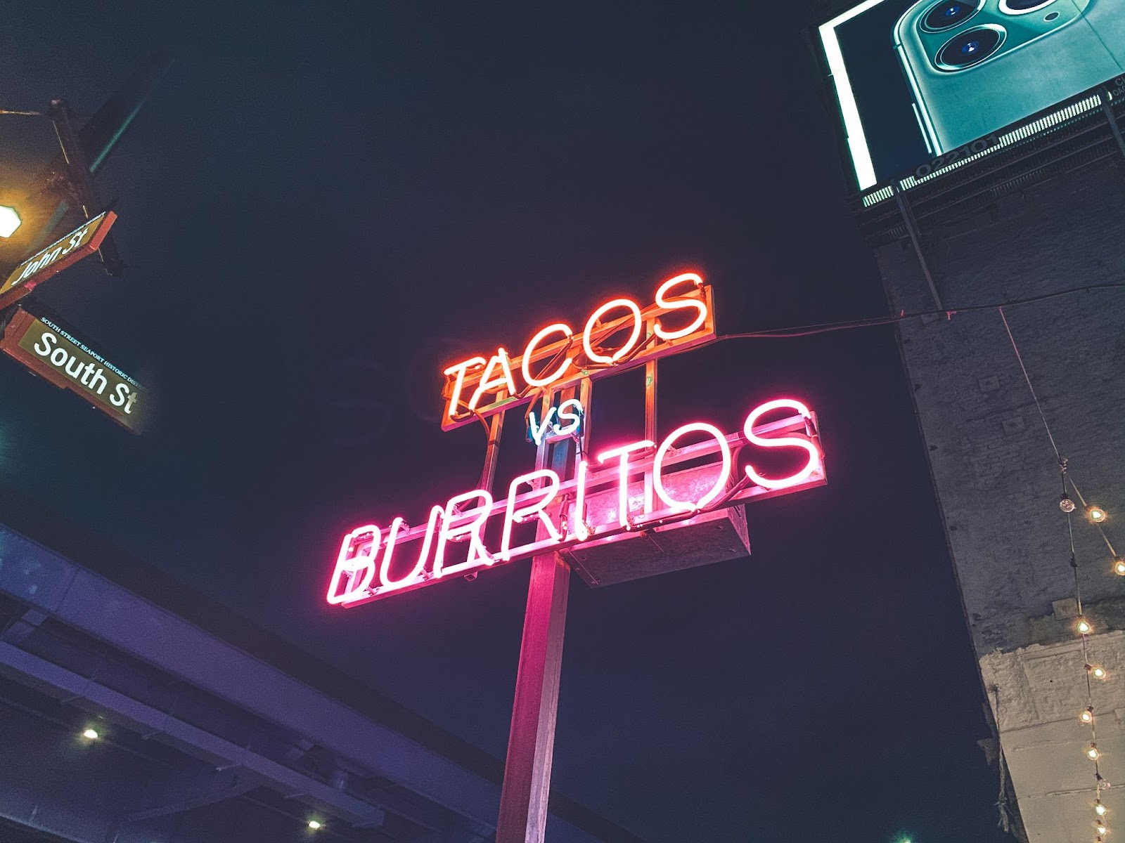 Tacos vs Burritos on a neon sign against a dark sky