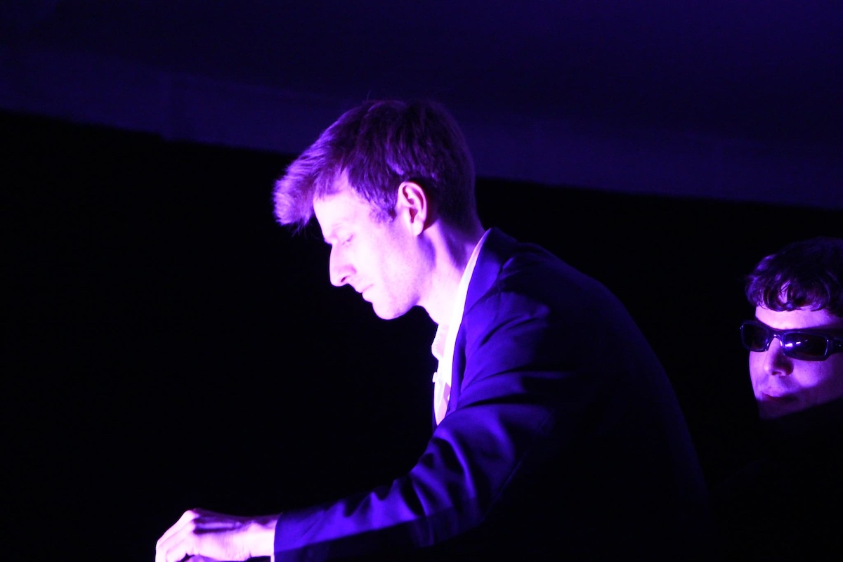 person looking down in a low light room and playing an instrument
