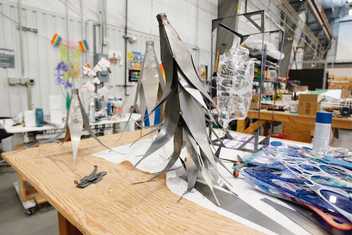 A metal scuplted banana sits atop a wooden working desk. 
