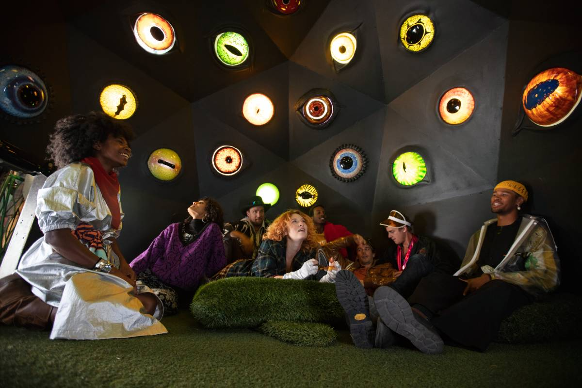 group of adults in meow wolf santa fe room with eyes one the walls