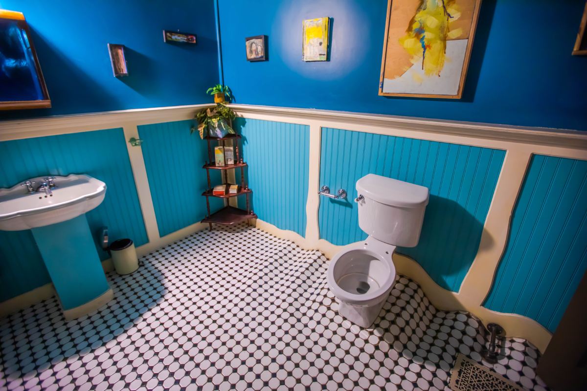 A blue bathroom with black and white tiling and a wave in the flooring.
