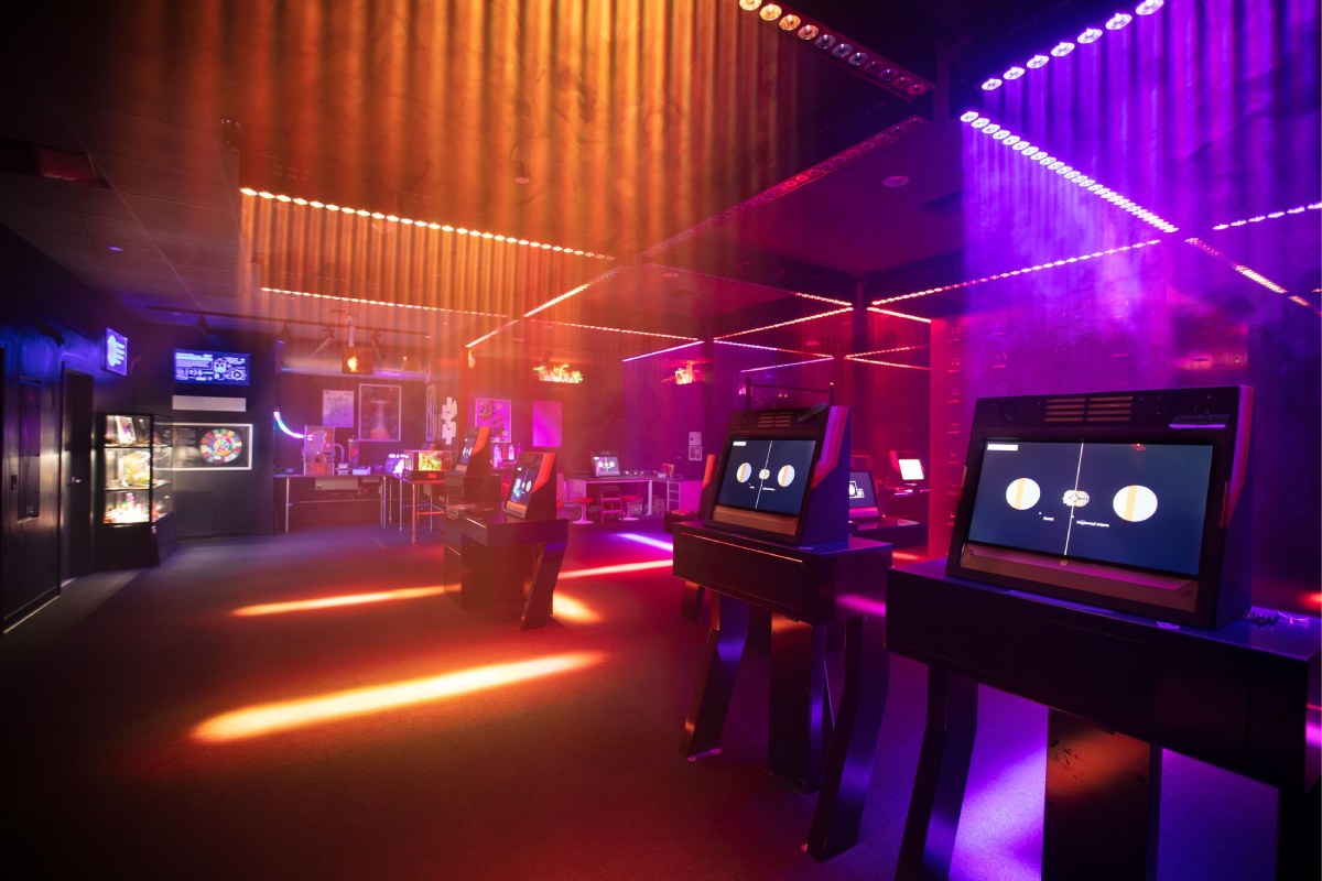 A set of kiosks with circles on them and purple and yellow lights streaming from above.