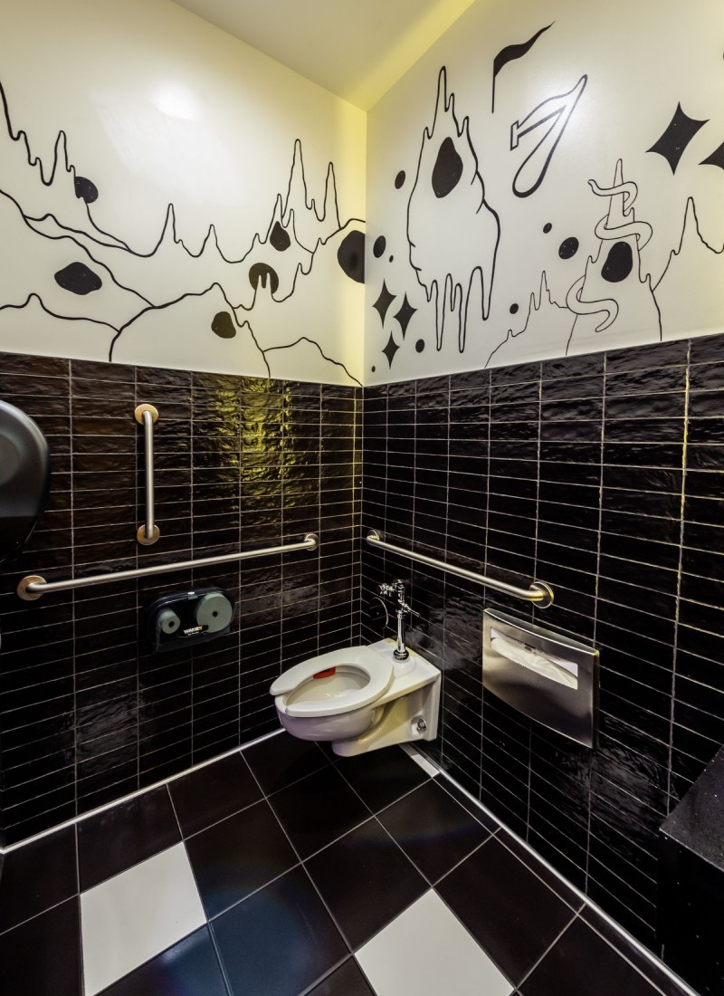 A restroom with drawings of black and white cave cartoons at the top.