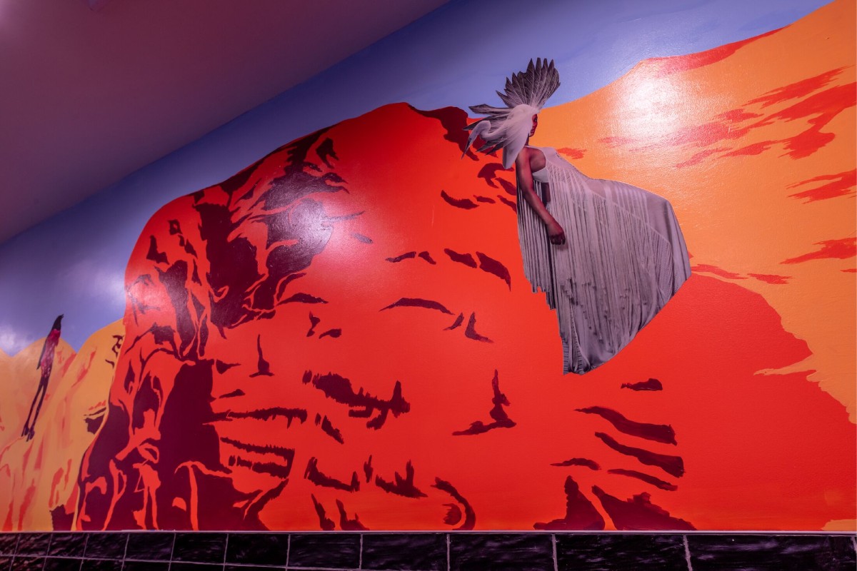 A painting of a red rock and a human figure leaning against it.