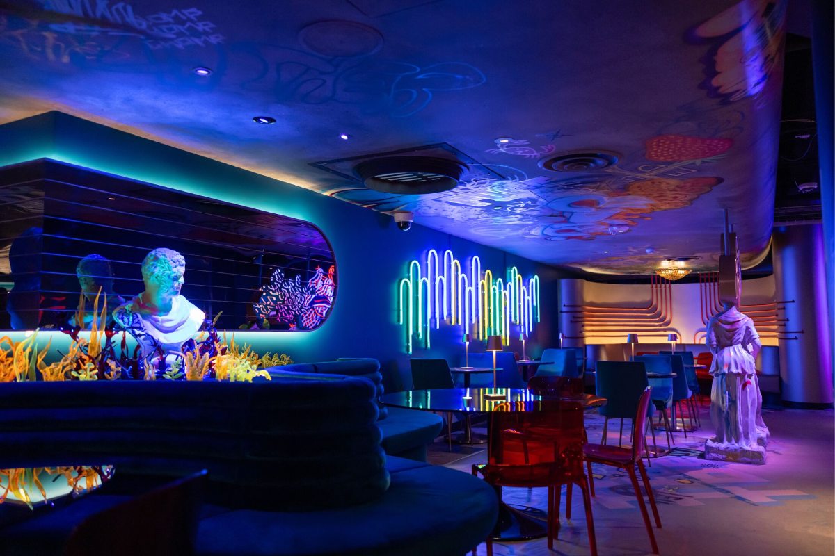 A lounge space with neon lights and white busts.