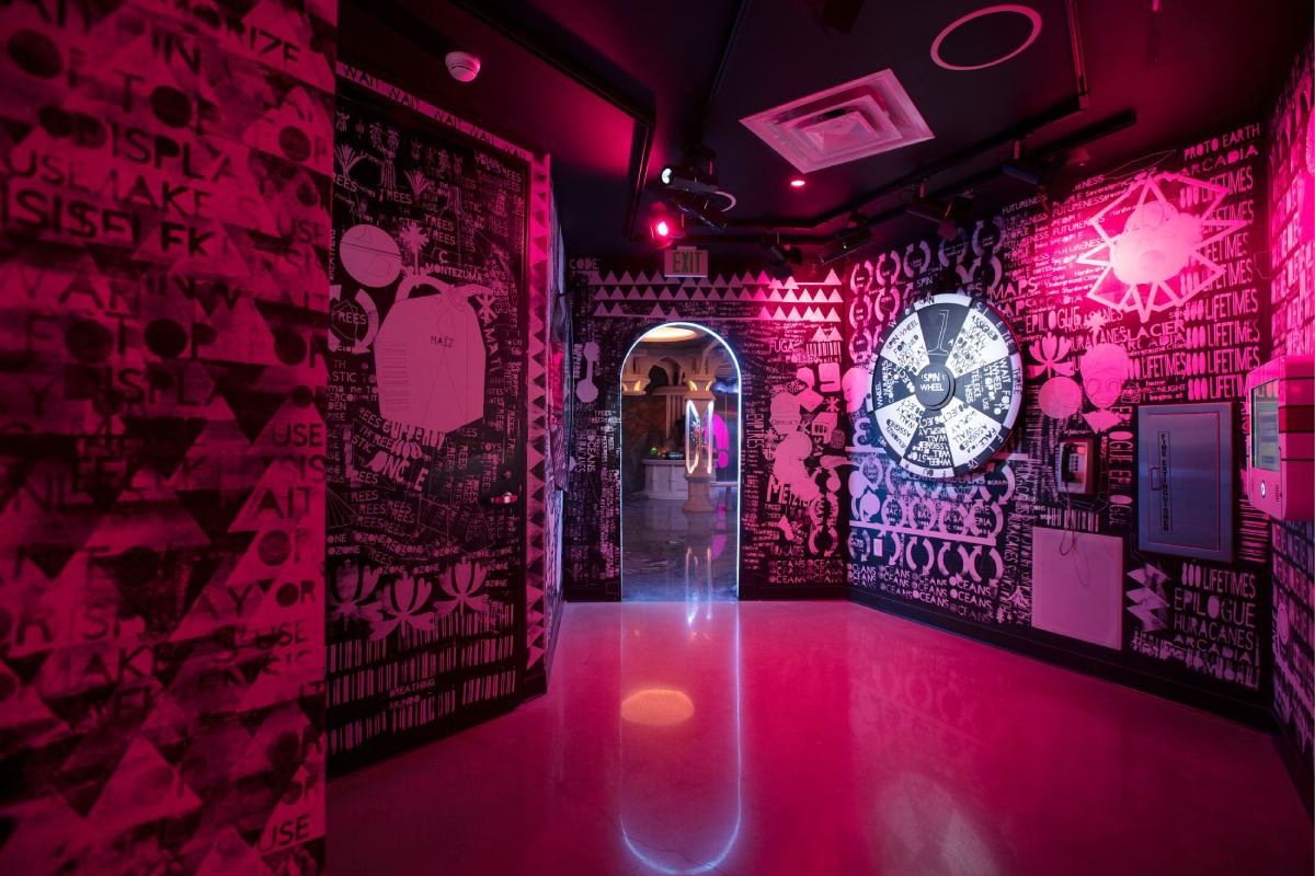 A room with pink lighting and different black and white wallpapering on the walls.