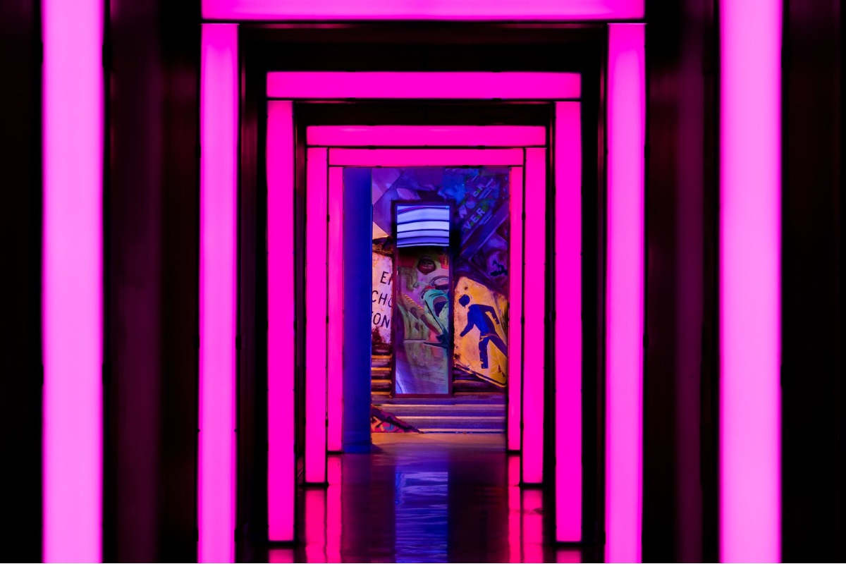 A hallway with pink lights around the walkway leading to a door.