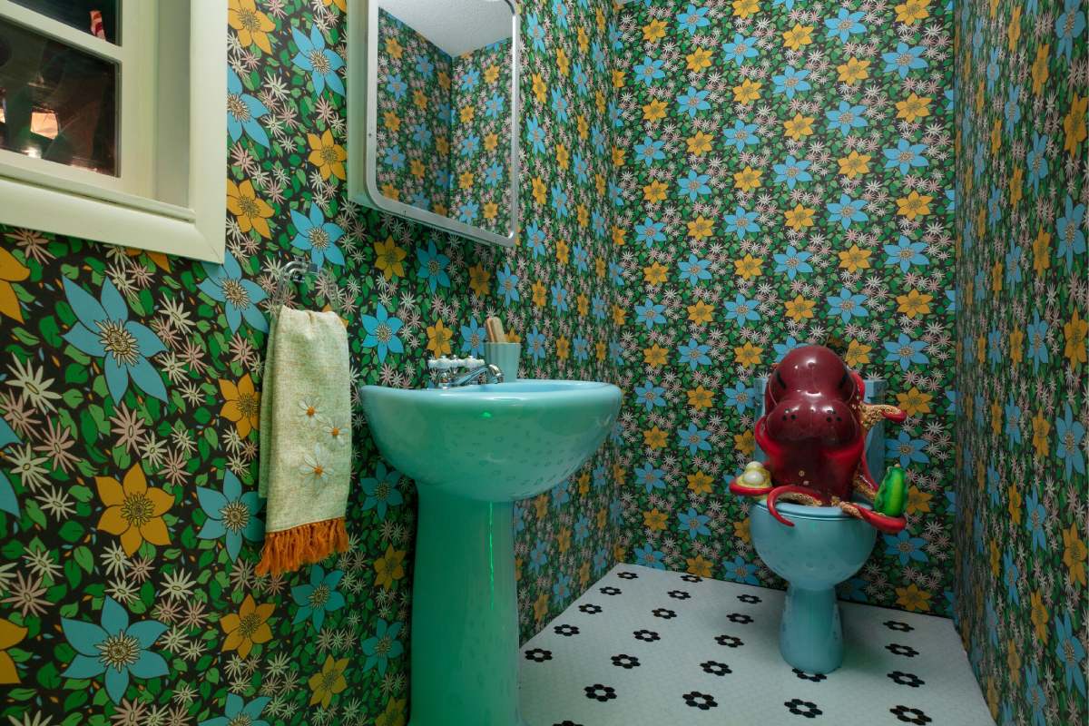 A flower-patterned bathroom with an octopus hippo on the toilet.