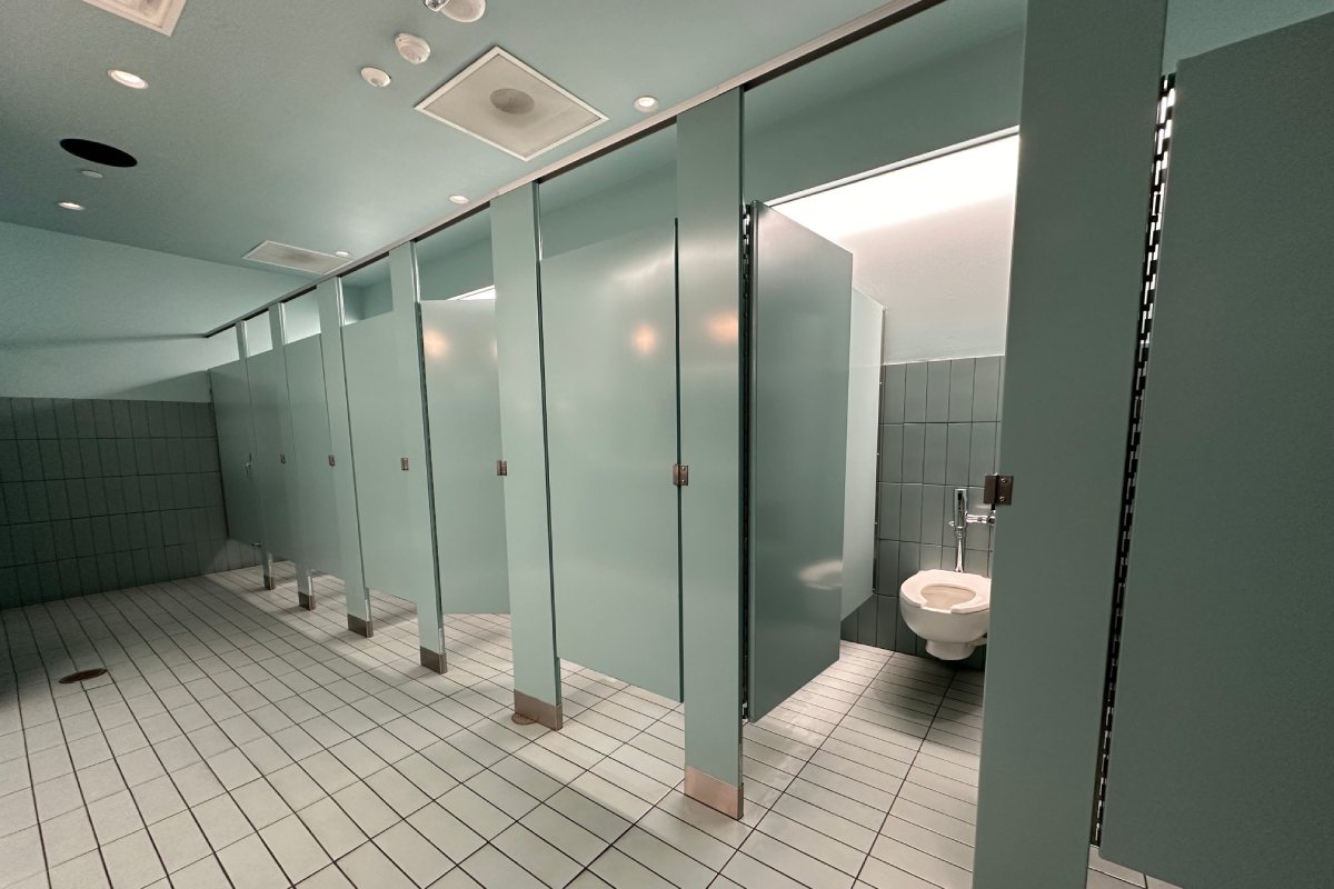 A row of bathroom stalls with one door open to a toilet.