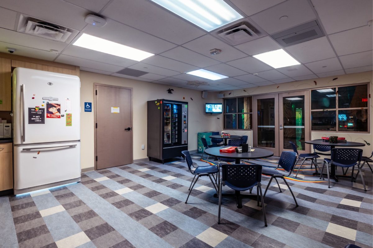 A breakroom with a table and chairs and a refrigerator.
