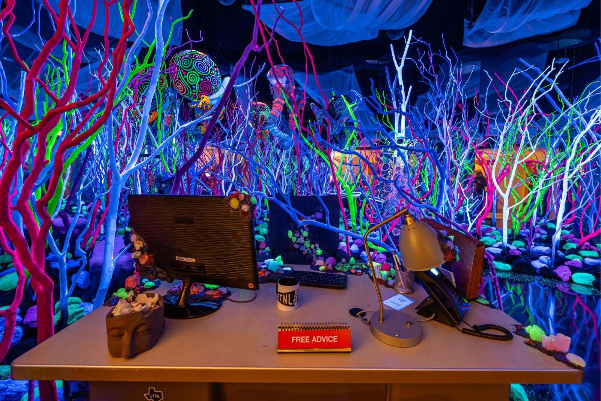 A desk with a computer sits in a sea of neon coral.