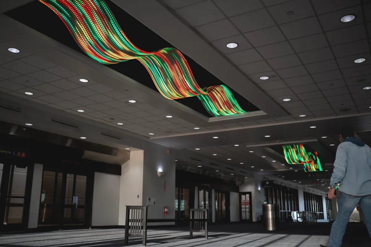 Colorful LED strips forming waves on the ceiling of an airport terminal