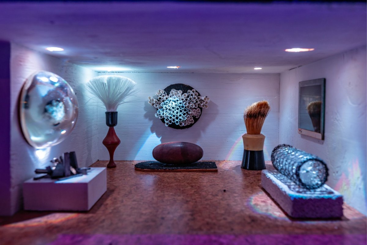 A small room diorama with a rock in the center and different mini furniture pieces.