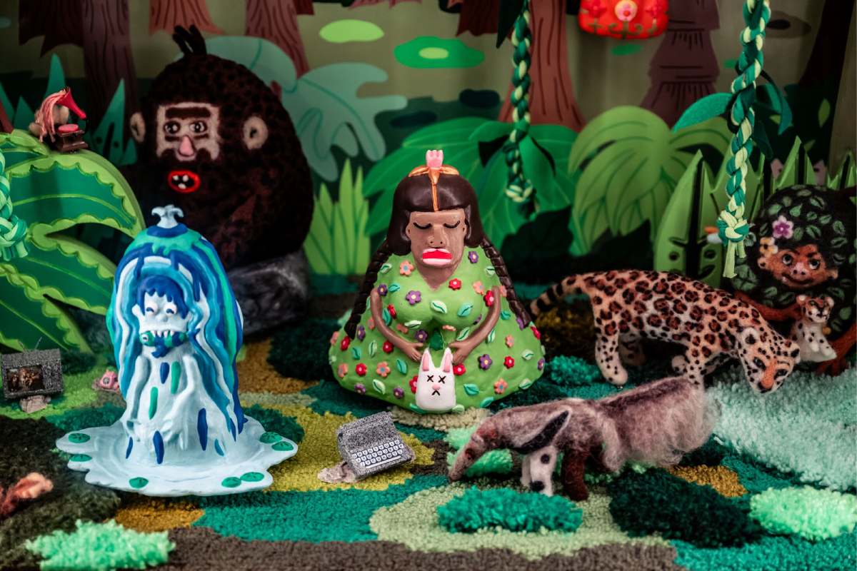 A clay scene of a person sitting in the center with different animals and creatures around them.