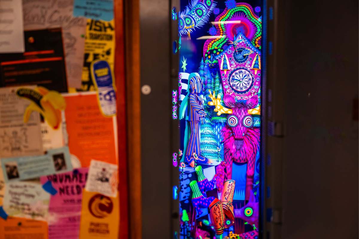 A door that opens to a neon space with a creature and a clock.