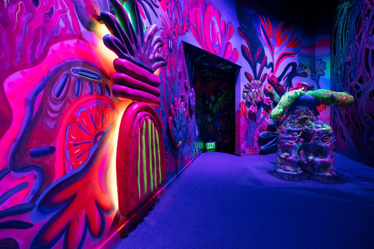 A room with pink coral shapes on the walls and a sculpture on the right.