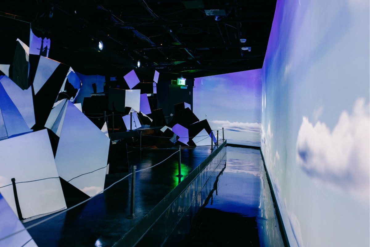 A room with a sky projected on the main side wall and other smaller monitors.
