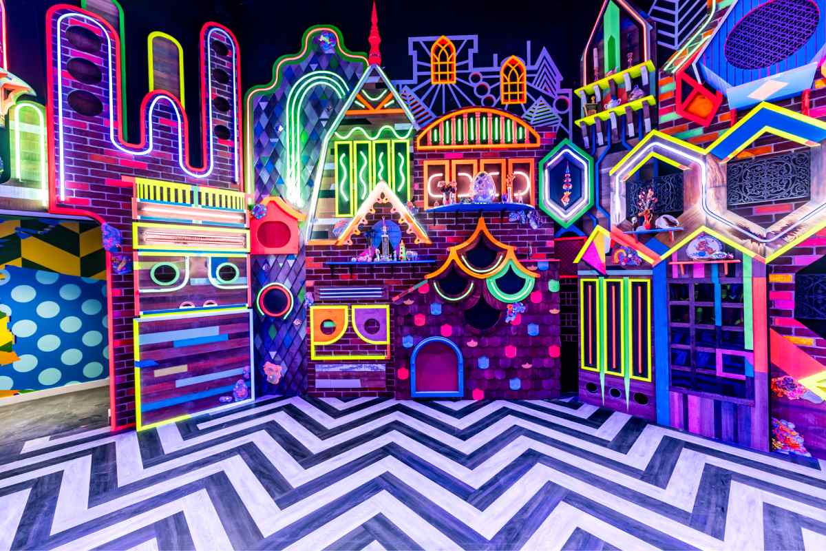 A neon, multicolored house with a chevron black and white striped stage.