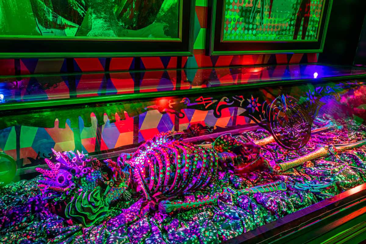 A skeleton of a creature with a fish face lays in a glass case with two framed photos behind it.