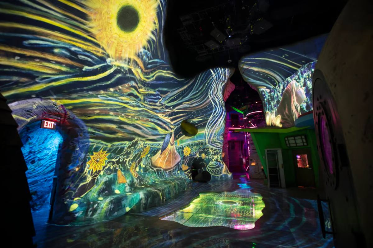 A room with projections on the walls of yellow and blue stripes and a sun-like shape up top.