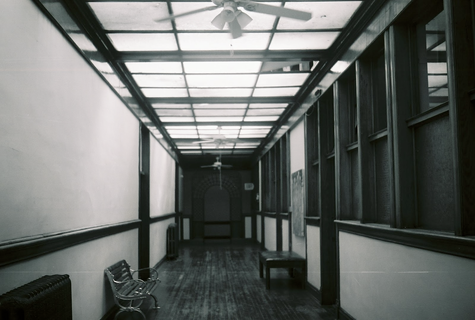 a black and white hallway photo with a bench on the left