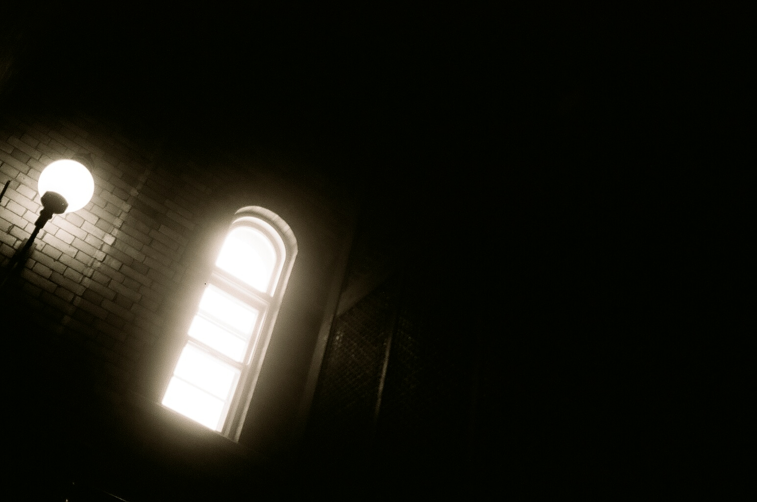 lamp lighting up a dark walkway and brick building
