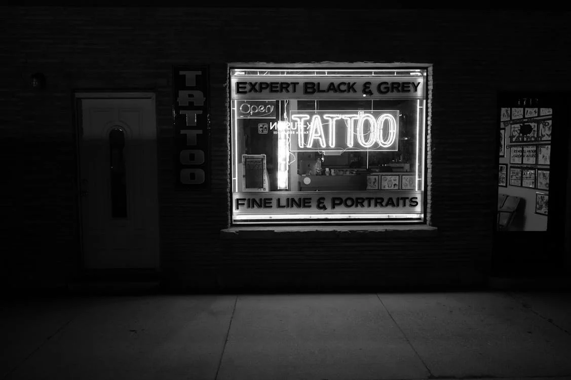 Lit up tattoo parlor sign on the sidewalk