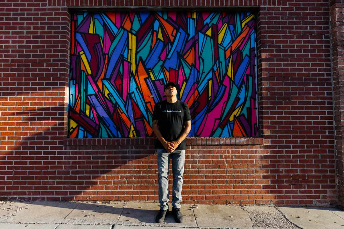 Man standing in front of a colorful abstract mural.