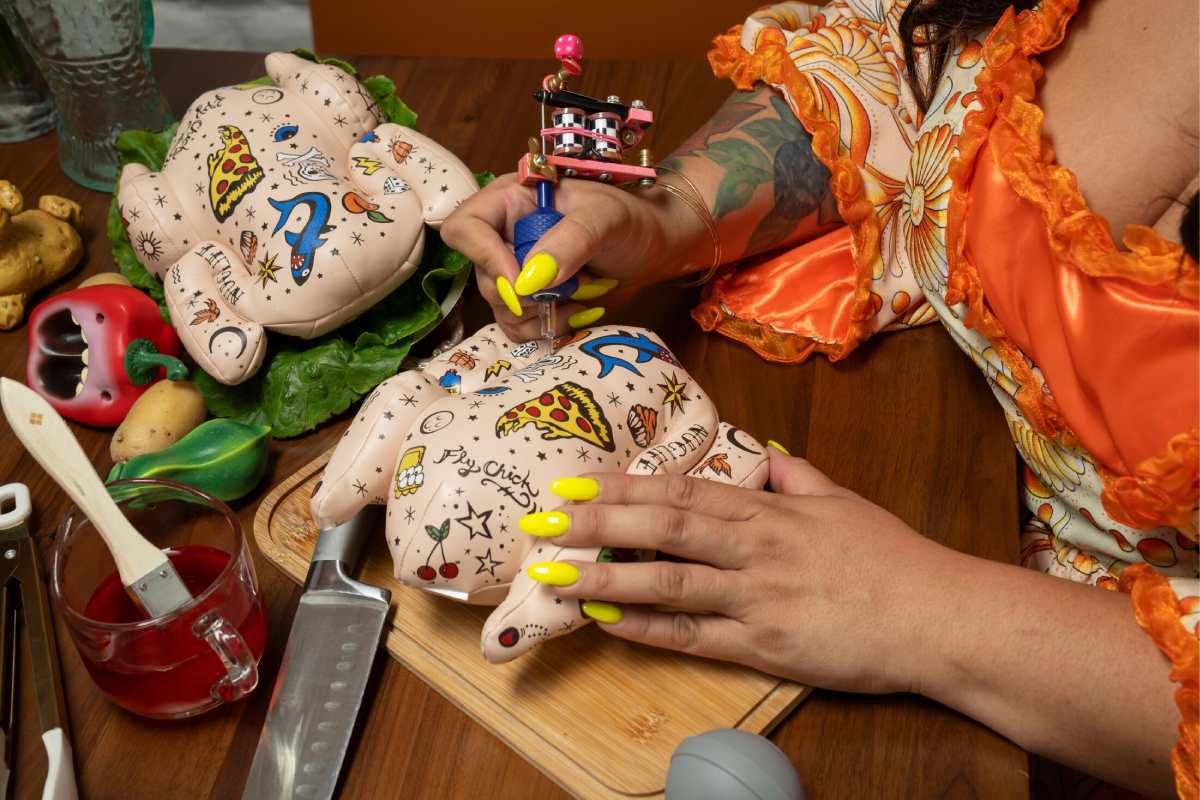 A person tattoos a chicken shaped plushie on a dinner table.