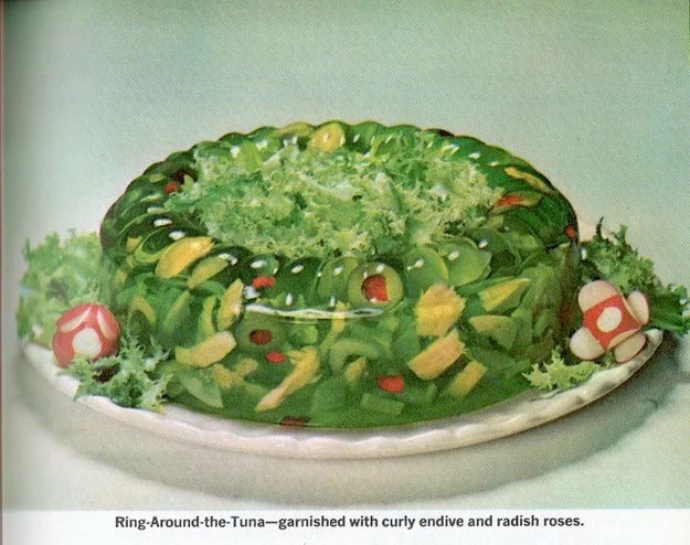 A gelatin recipe called “Ring Around The Tuna,” a green gelatin ring rife with pimento olivas and avocado. The center contains tuna dyed green.