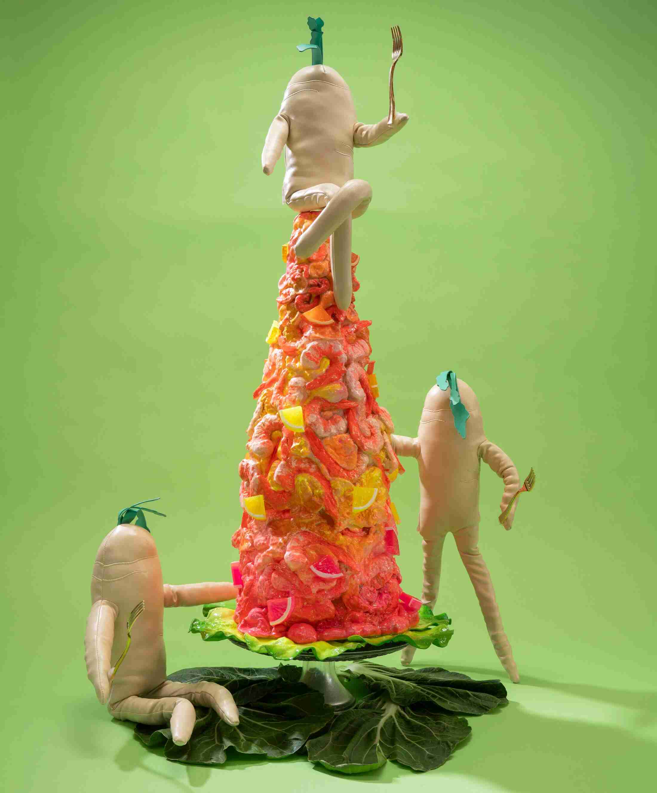 Three anthropomorphic daikons scale a bright pink-and-yellow conical shrimp tower against a green backdrop.
