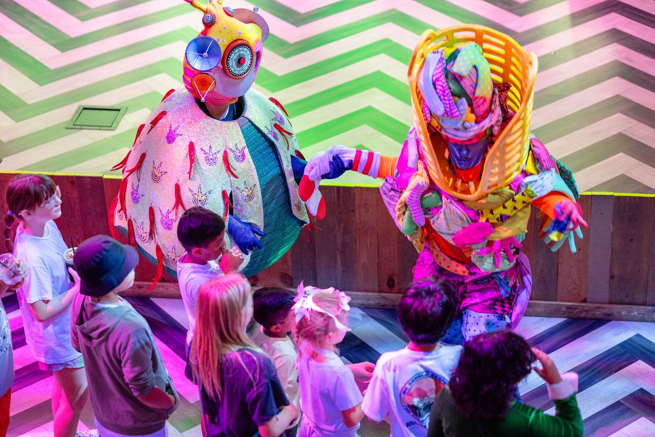 two otherworldly beings interacting with kids at Meow Wolf