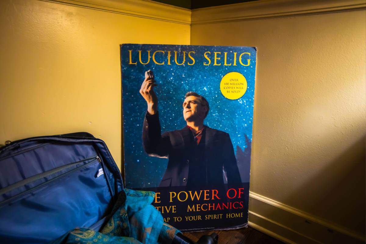 A book with Lucius Selig holding something in his hand in the air and looking at it with a galaxy background.