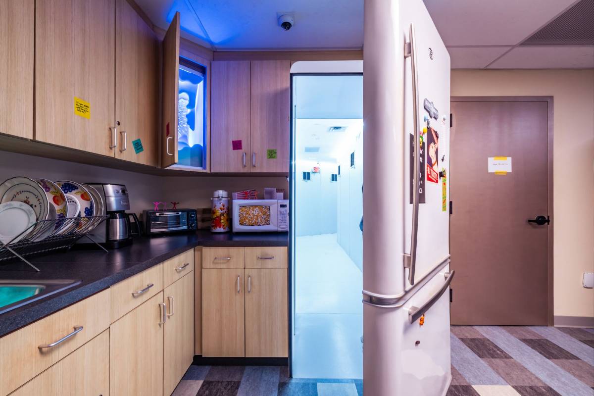 A radio station break room with an open fridge door leading to an unknown place.