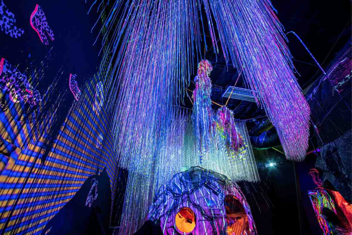 Blue and purple tinted strings hanging from a ceiling above an orb shape.