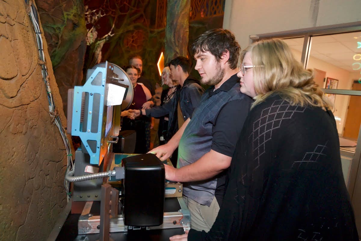 two people focusing on a computer screen inside Meow Wolf Houston