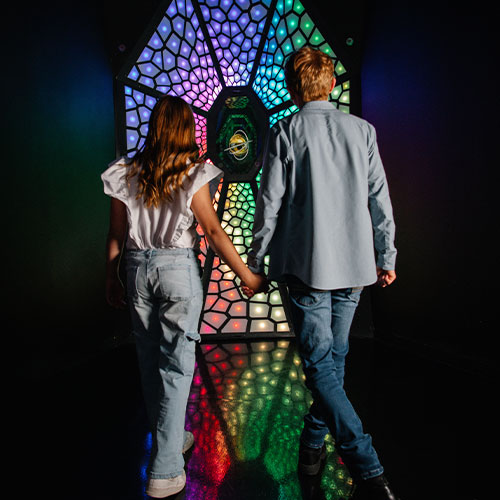 a couple holding hands at meow wolf grapevine in front of an art installation