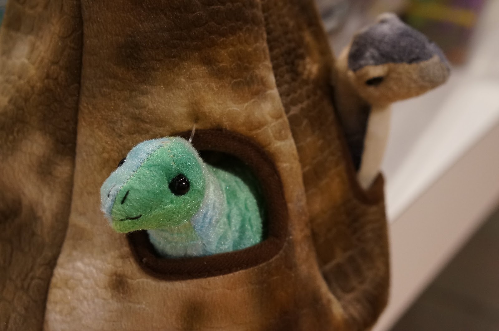A dinosaur head peeks out of a pouch at the Houston Toy Museum