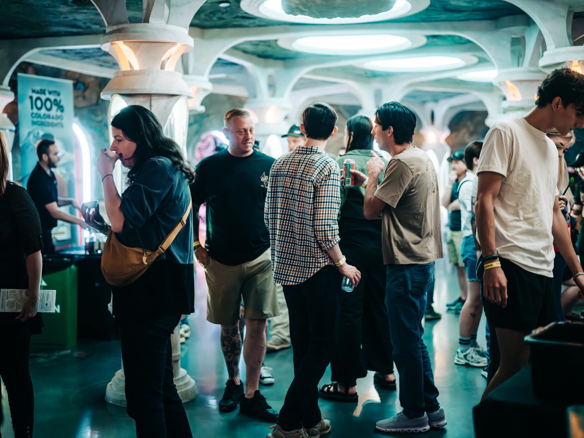 people standing in a bright cave-like space, mingling and looking at vendors