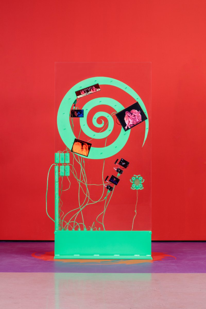 A red background with a green, wired port at the bottom that transitions to a green swirl at the top.