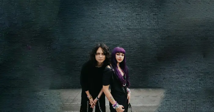 Siblings Tinzo and Jojo are the co-founders and resident DJs behind the New York based YouTube channel and party, Book Club Radio, coming to Fancy Town in April. These two are standing against a black brick wall.