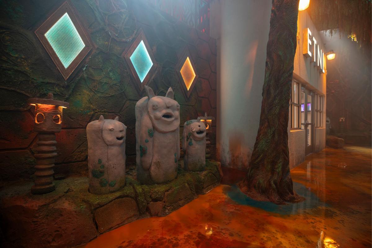 Round forest creatures standing guard near a radio station door at Meow Wolf Houston