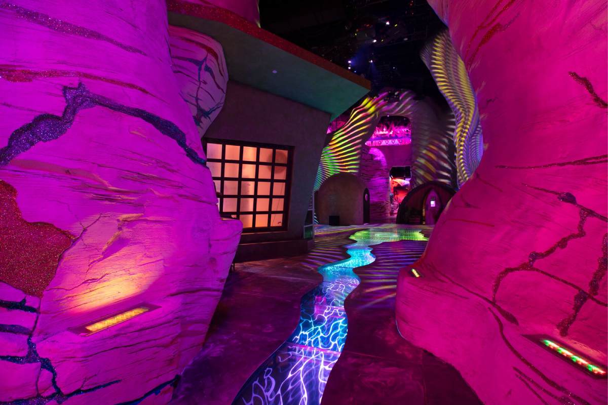 A pink desert-like area with a multicolored river through the center.